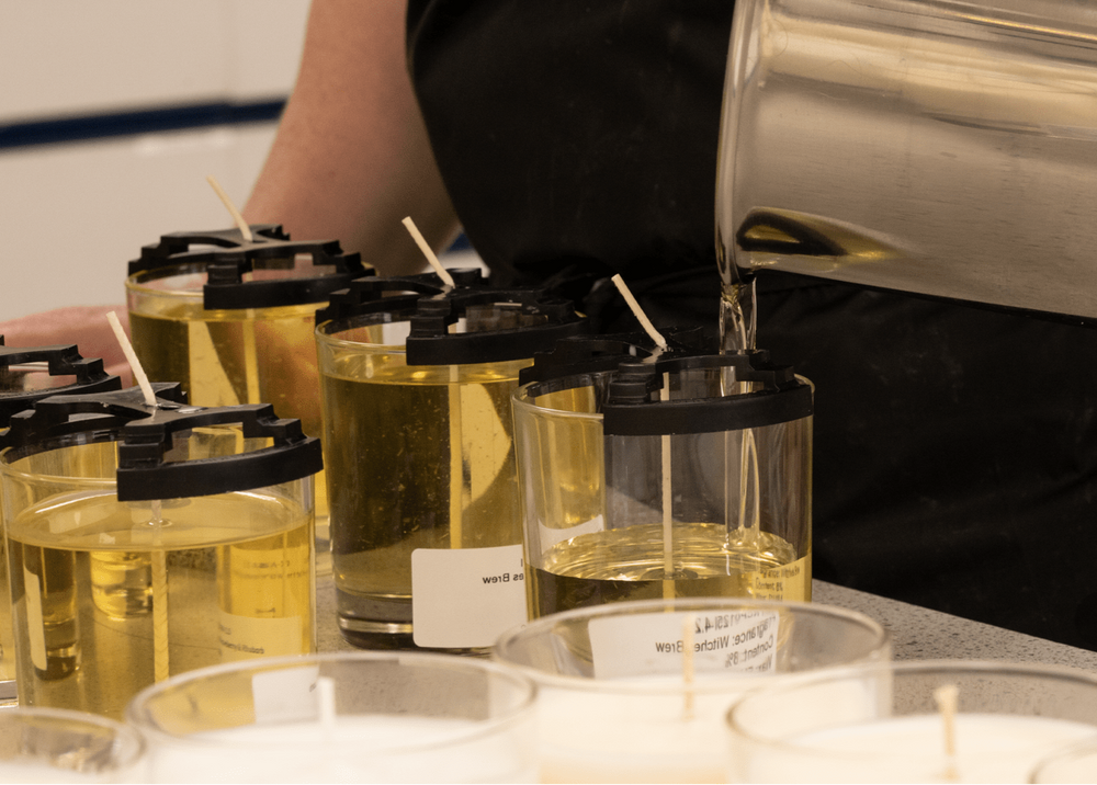 Person pouring liquid into small containers with a focus on the action.