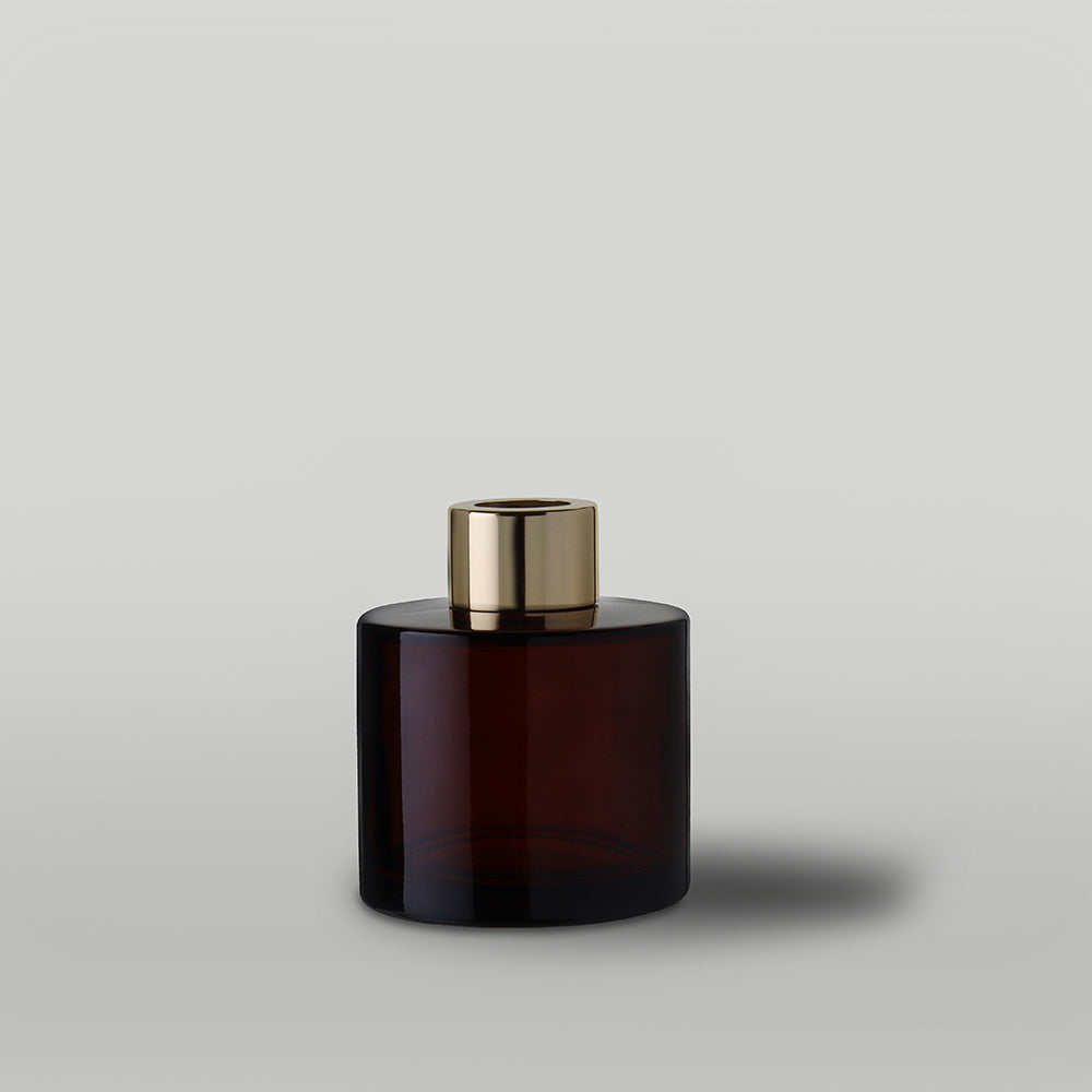 Amber diffuser bottle with gold cap on a light gray background