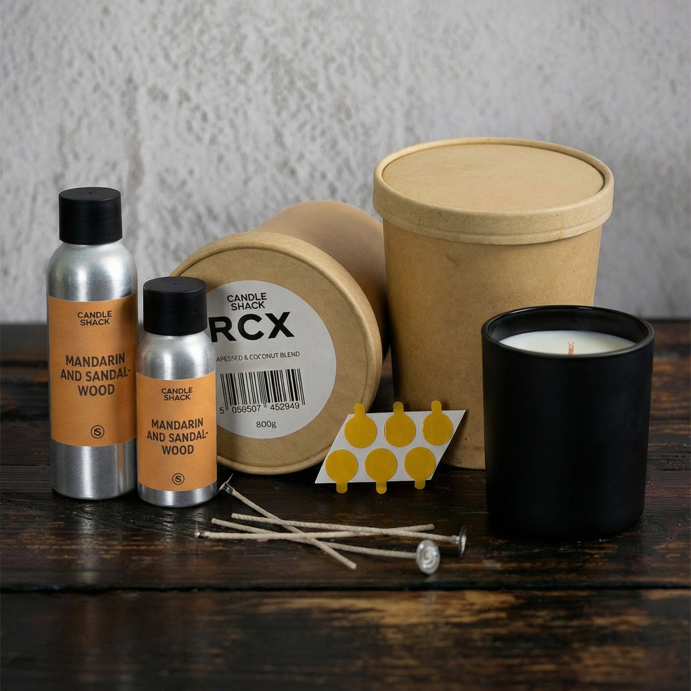 Candle-making kit including candle jars, wicks, and containers on a wooden surface.
