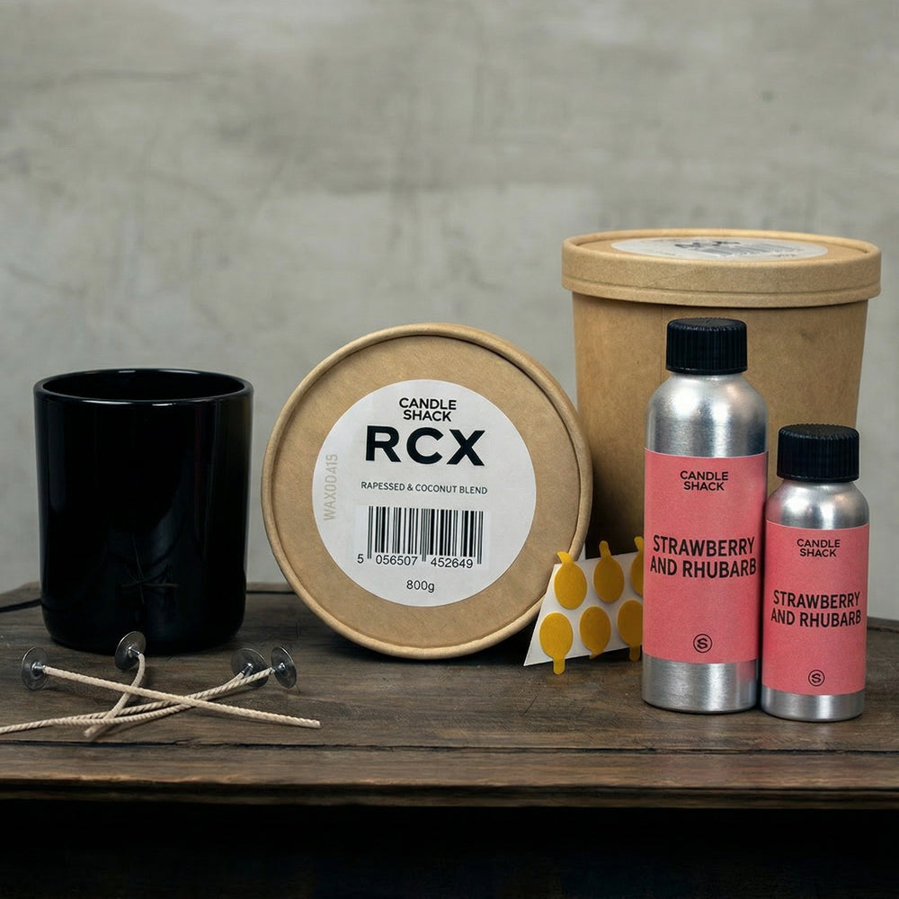 Candle Shack kits including a black candle jar, RCX container, and Strawberry and Rhubarb fragrance oil on a wooden surface.
