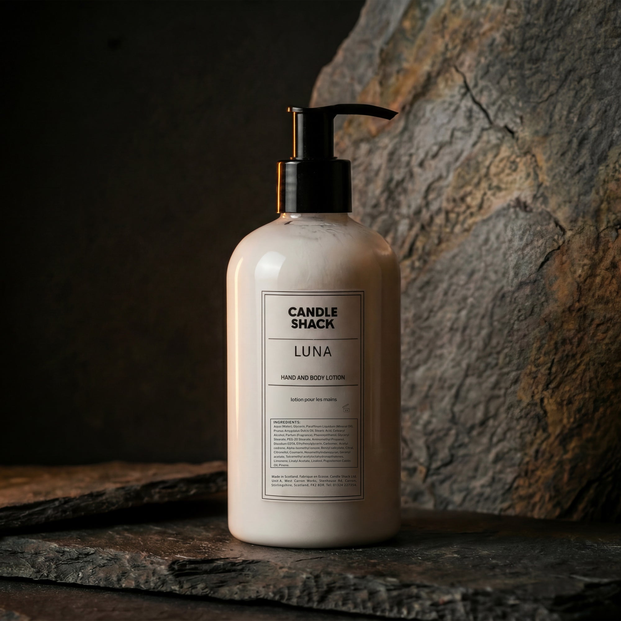 Lotion bottle labeled 'Candle Shack Luna' on a stone surface with a dark background