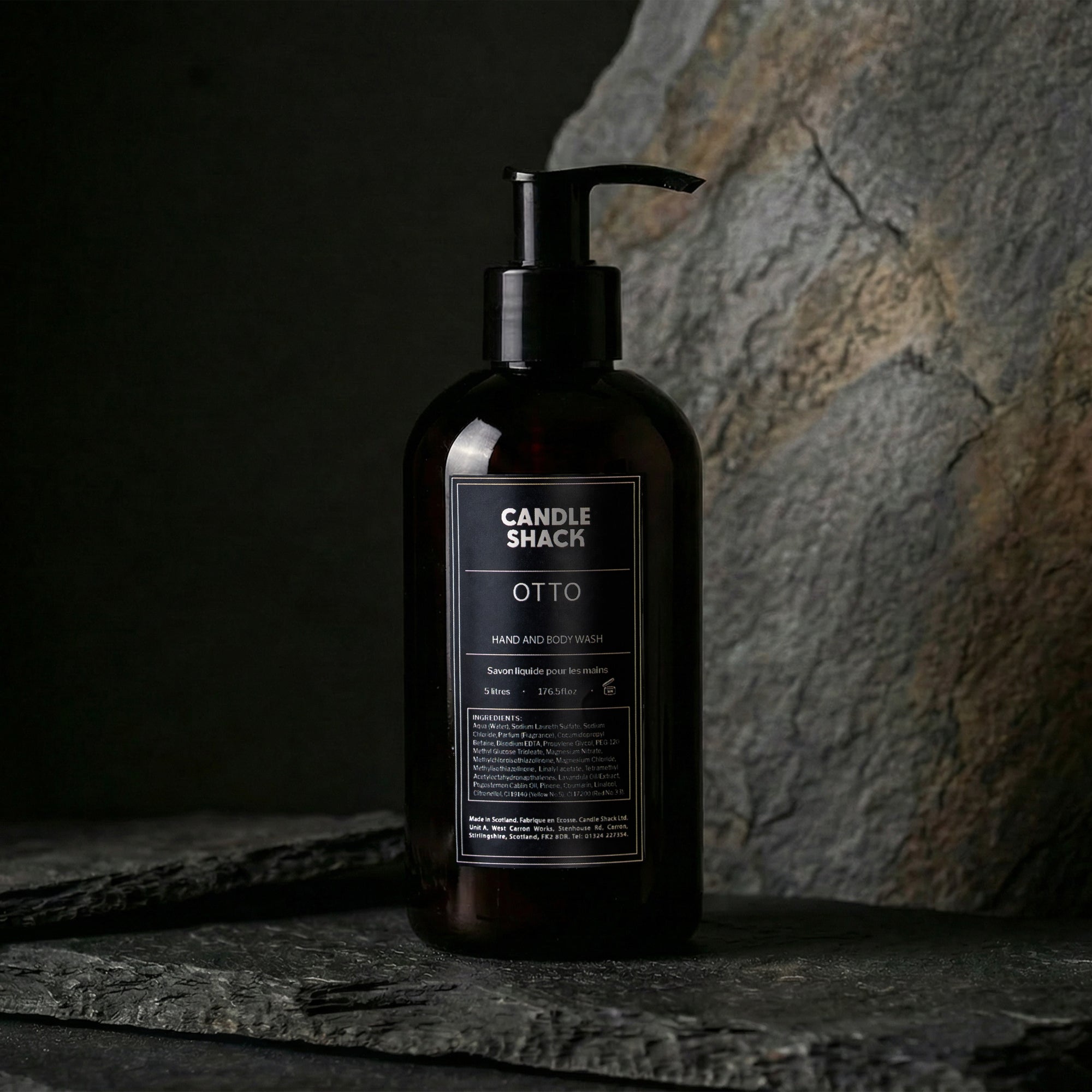 Black bottle Hand and body wash with pump labeled 'Candle Shack Otto' on a dark stone surface.
