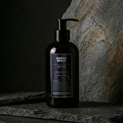 Black bottle Hand and body wash with pump labeled 'Candle Shack Otto' on a dark stone surface.