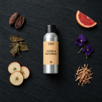 Cocoa & Patchouli fragrance oil - Candle Shack aluminium bottle with dried botanicals on a dark slate background