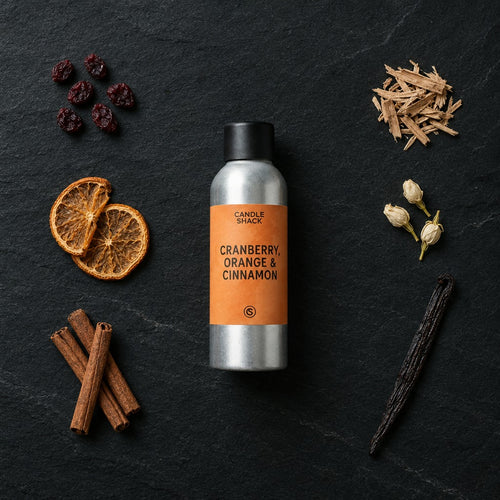 Cranberry, Orange and Cinnamon fragrance oil - Candle Shack aluminium bottle with dried botanicals on a dark slate background