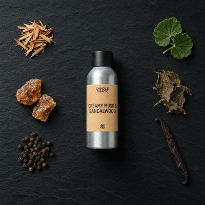 Creamy Musk and Sandalwood fragrance oil - Candle Shack aluminium bottle with dried botanicals on a dark slate background