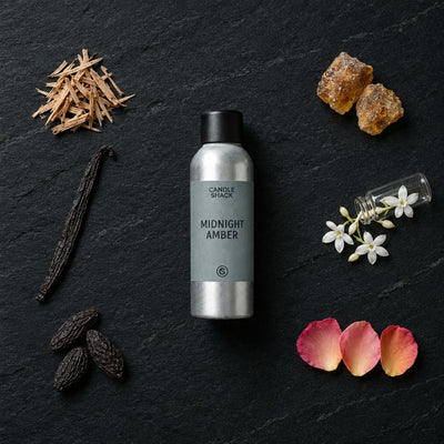 Midnight Amber fragrance oil - Candle Shack aluminium bottle with dried botanicals on a dark slate background