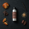 Pain Au Chocolat fragrance oil - Candle Shack aluminium bottle with dried botanicals on a dark slate background