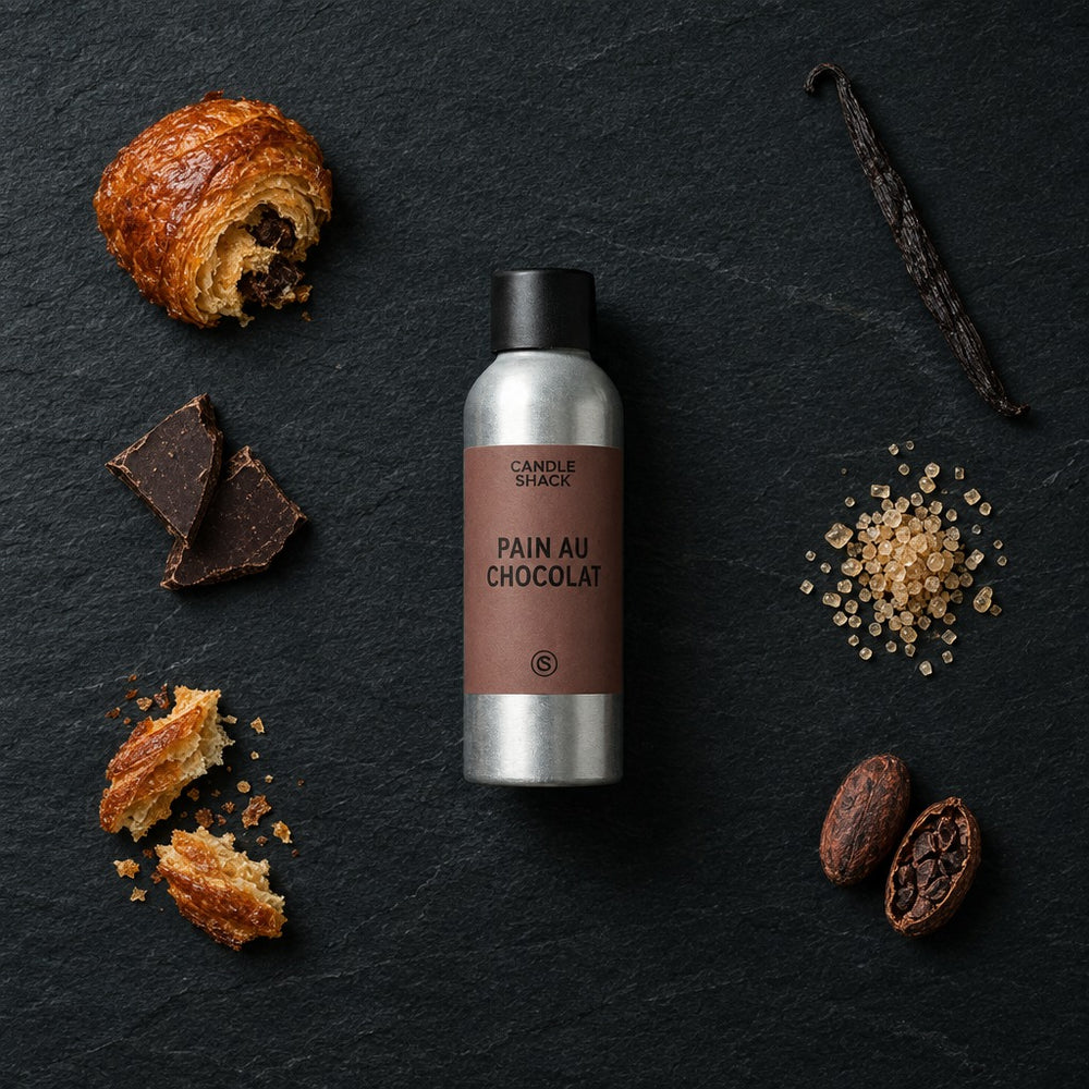 Pain Au Chocolat fragrance oil - Candle Shack aluminium bottle with dried botanicals on a dark slate background