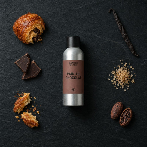 Pain Au Chocolat fragrance oil - Candle Shack aluminium bottle with dried botanicals on a dark slate background