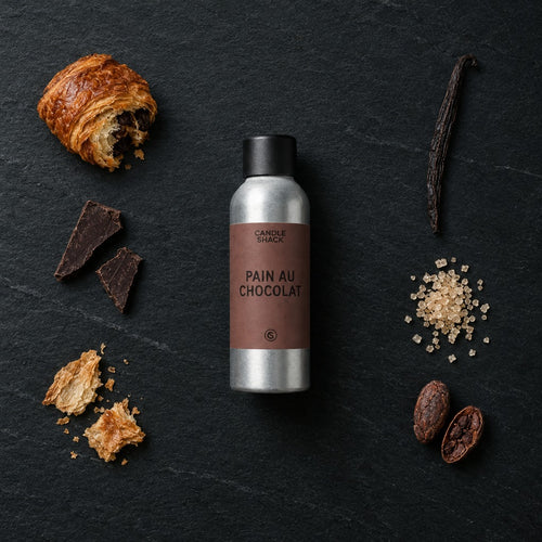Pain Au Chocolat fragrance oil - Candle Shack aluminium bottle with dried botanicals on a dark slate background