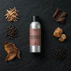 Sandalwood & Black Pepper fragrance oil - Candle Shack aluminium bottle with dried botanicals on a dark slate background