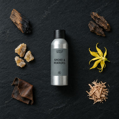 Smoke & Mirrors fragrance oil - Candle Shack aluminium bottle with dried botanicals on a dark slate background