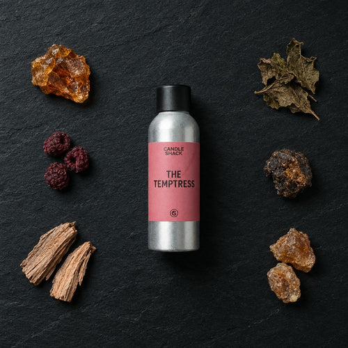 The Temptress fragrance oil - Candle Shack aluminium bottle with dried botanicals on a dark slate background