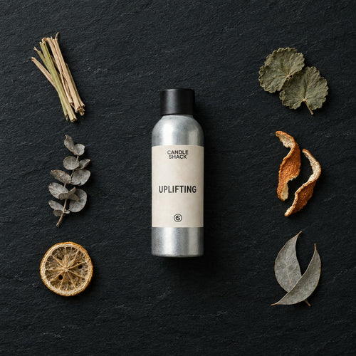 Uplifting Natural Oil fragrance oil - Candle Shack aluminium bottle with dried botanicals on a dark slate background