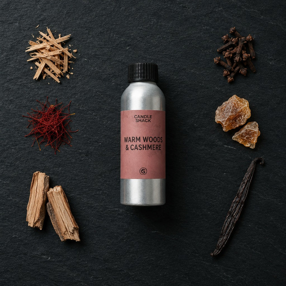 Warm Woods & Cashmere fragrance oil - Candle Shack aluminium bottle with dried botanicals on a dark slate background
