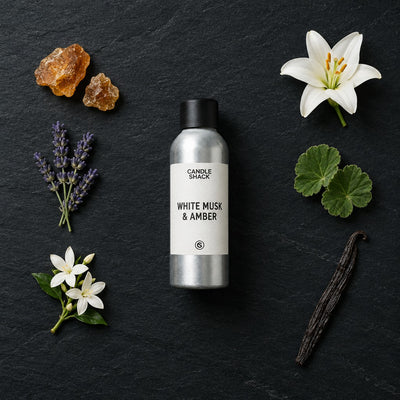 White Musk & Amber fragrance oil - Candle Shack aluminium bottle with dried botanicals on a dark slate background