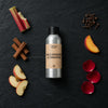 Wild Rhubarb & Cinnamon fragrance oil - Candle Shack aluminium bottle with dried botanicals on a dark slate background