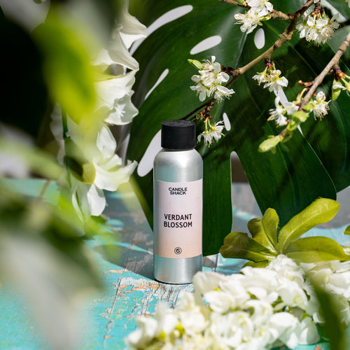 Verdant Blossom Fragrance Oil bottle surrounded by palm tree and white flowers